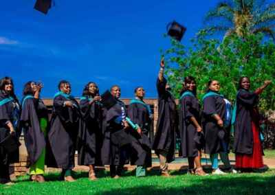 Group of graduates outdoors tossing caps into the air in celebration.