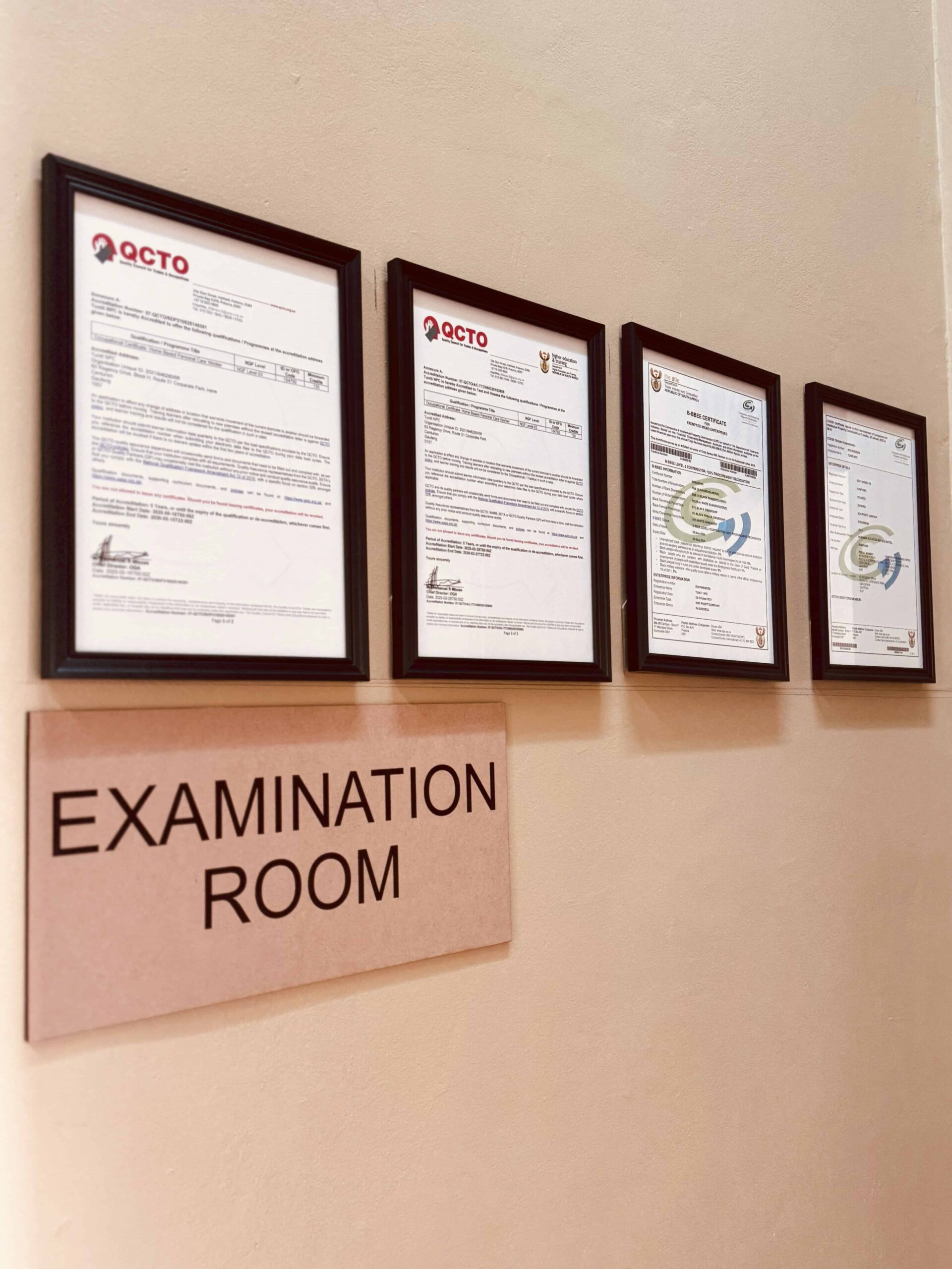 IMG_9023_post Wall with QCTO certificates and a sign reading 'Examination Room' in a professional setting.