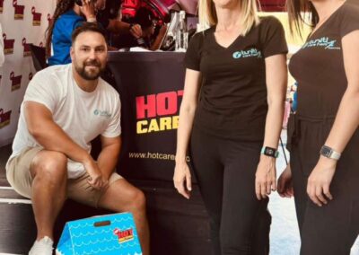 Tuniti Care Hero team posing with Hot 102.7 FM radio crew at event.