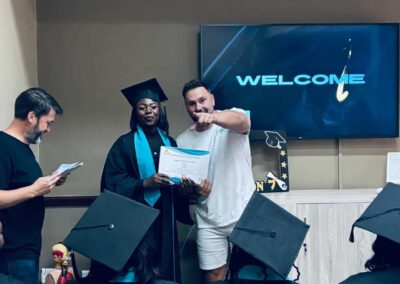 Graduate receiving certificate from man in white shirt at indoor ceremony.