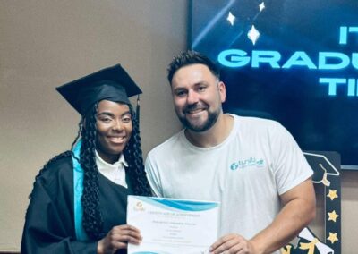 Graduate and Tuniti team member smiling while holding certificate at ceremony.