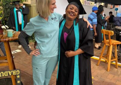 Smiling graduate with woman in scrubs during outdoor celebration.