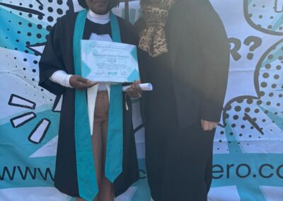 Two women posing in a graduation frame with green field in the background.