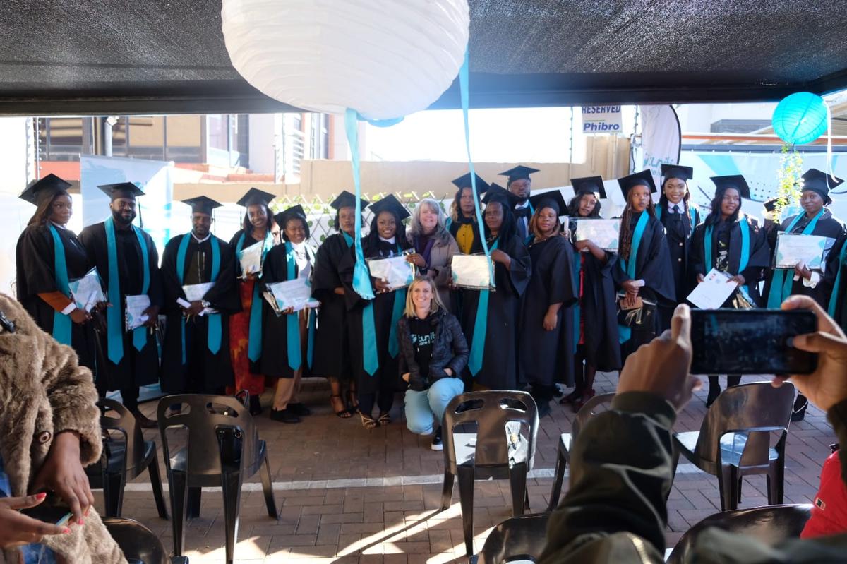 image14 Graduates proudly pose with certificates and teal sashes at Tuniti Care Hero caregiver graduation ceremony under festive canopy decor.