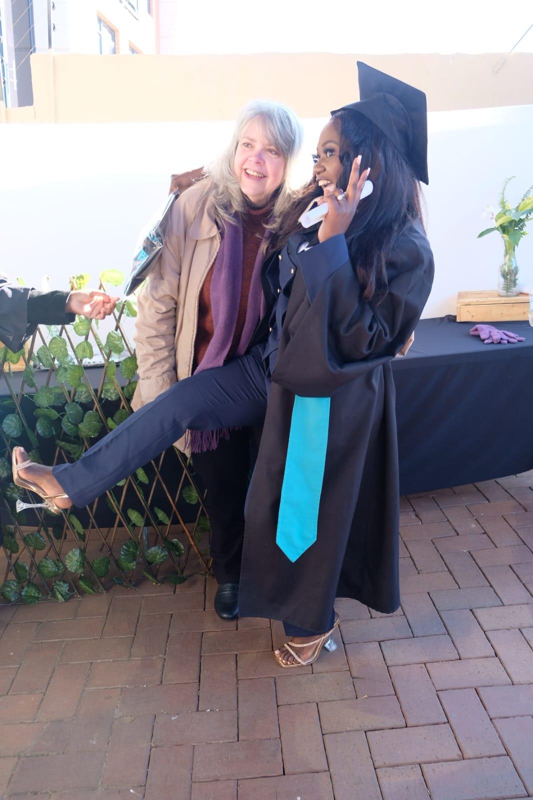 image16 Joyful graduate in cap and gown playfully posing with a proud supporter during caregiver graduation ceremony, showcasing celebration and achievement.