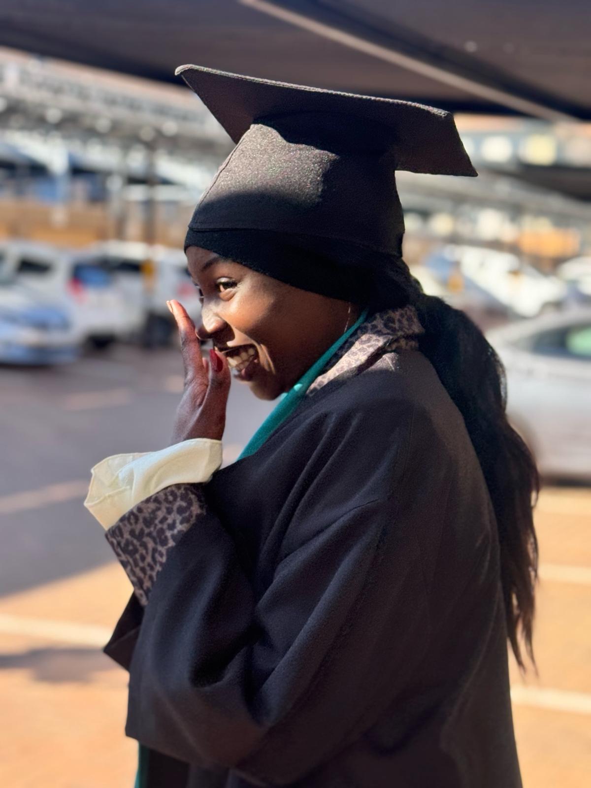 image2 Emotional female graduate in cap and gown smiling with hand over face, capturing a joyful moment of accomplishment at a caregiver training ceremony.