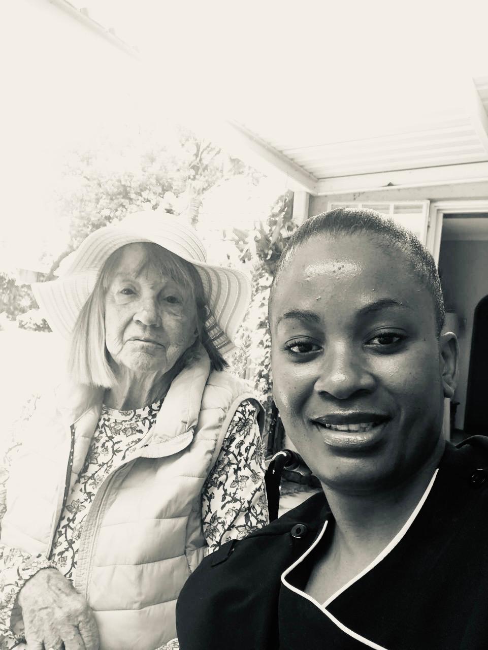 Smiling caregiver taking a selfie with elderly woman in sunhat, capturing a warm and supportive moment in senior home care or assisted living setting.